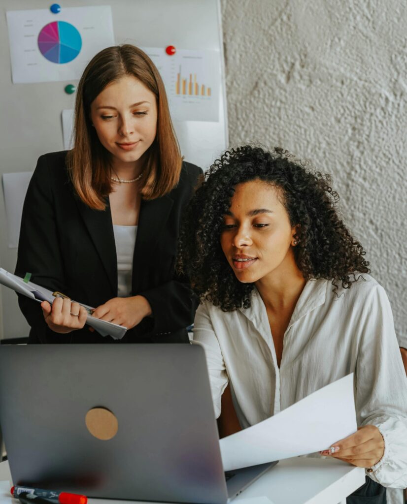 Two confident women working together on a project in a modern office.